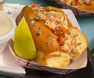 カットレモンが添えられたロブスターロールの写真